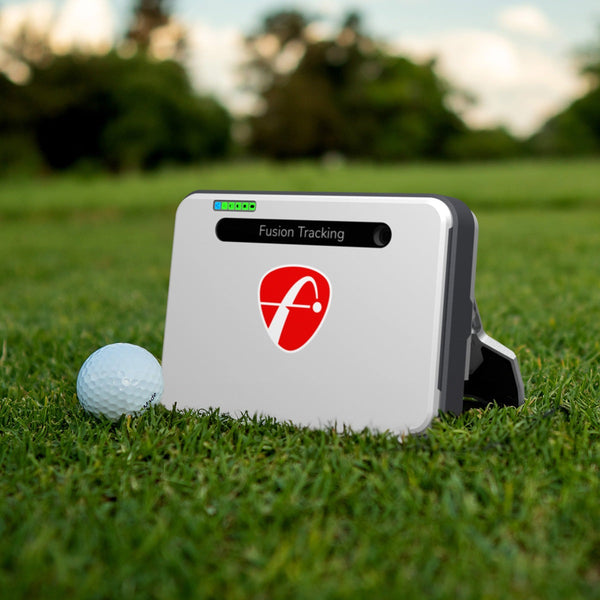 Launch Monitors - Fusion Tracking device placed on grass next to golf ball for accurate swing analysis.