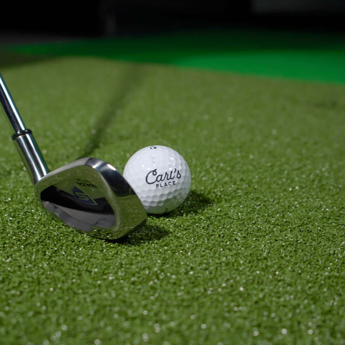 Golf club and ball resting on Carl's Place HotShot Golf Hitting Mat, showcasing premium turf for practice.